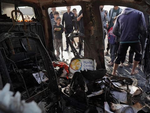 People gather around the carcass of a car used by US-based aid group World Central Kitchen, that was hit by an Israeli strike in Deir Al Balah in the central Gaza Strip on April 2, 2024.