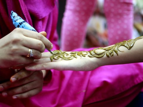 Women decorate their hands with traditional henna designs at a beauty salon in Dubai
