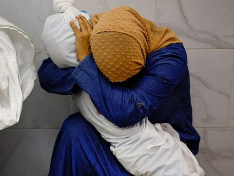 Palestinian woman Inas Abu Maamar, 36, embraces the body of her 5-year-old niece Saly, who was killed in an Israeli strike, at Nasser hospital in Khan Younis in the southern Gaza Strip, October 17, 2023.