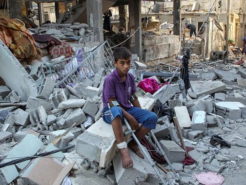 A wounded Palestinian sits on debris at the site of an Israeli strike on a house, amid Israel's ongoing war in Gaza