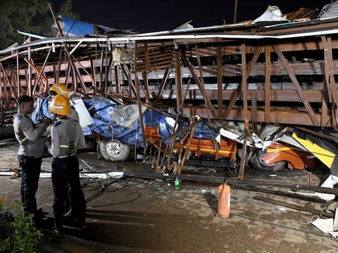 Firefighters stand next to the damaged vehicles trapped in the debris after a massive billboard fell during a rainstorm in Mumbai, India, May 13, 2024.