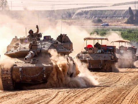 Israeli army battle tanks move near the border with the Gaza Strip at a location in southern Israel.