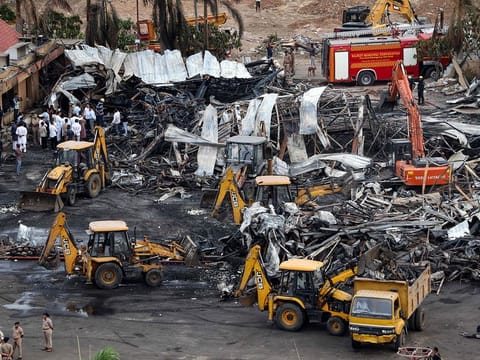 Officials clear charred remains at the site of a fire accident.