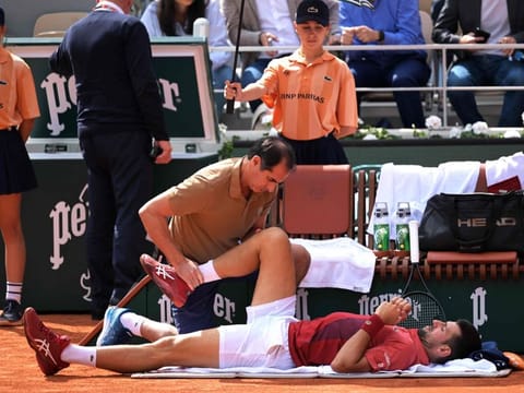 Serbia's Novak Djokovic receives medical treatment during his men's singles round of 16 against Argentina's Francisco Cerundolo on Court Philippe-Chatrier on day nine of the French Open tennis tournament at the Roland Garros Complex in Paris on June 3, 2024. (Photo by Bertrand GUAY / AFP)