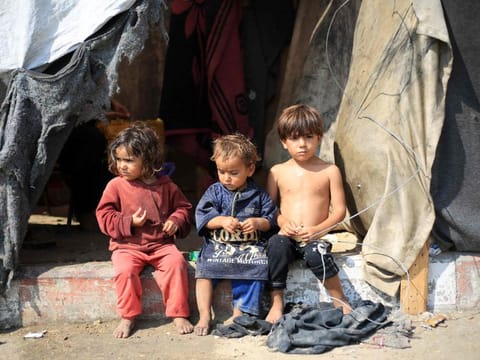 Displaced Palestinian children sit in front of a tent used as temporary shelter in Deir Al Balah in the central Gaza Strip on July 7, 2024.