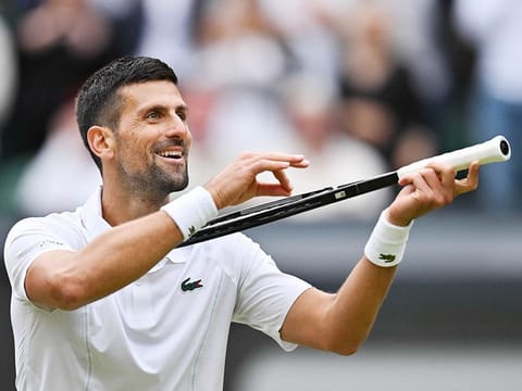 Serbia's Novak Djokovic imitates playing the violin with his racquet as he celebrates winning against Italy's Lorenzo Musetti during their men's singles semi-final tennis match of the 2024 Wimbledon Championships at The All England Lawn Tennis and Croquet Club in Wimbledon, southwest London, on July 12, 2024.
