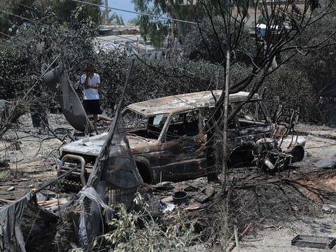 A Palestinian man looks at a burnt out vehicle following an Israeli military strike on the Al Mawasi camp for internally displaced people (IDP), near the city of Khan Yunis, southern Gaza Strip on July 13, 2024.