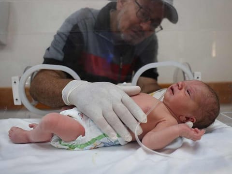 Baby Malek Yasine, who was reportedly delivered by Cesarean section after his 9-months pregnant mother succumbed to her injuries sustained during an overnight Israeli strike on Nusseirat in the central Gaza Strip, is caressed by his grandfather as he lies in an incubator at the Al Awda hospital in Deir El Balah on July 20, 2024.