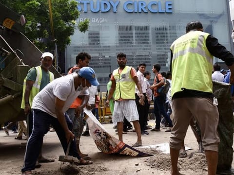 Delhi Municipal Corporation (MCD) workers outside the Rau’s IAS Study Centre in Old Rajinder Nagar, New Delhi, on July 28, 2024, amid a student protest following the deaths of three civil service aspirants who drowned in the coaching centre's basement due to flooding.