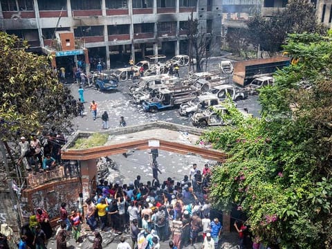 People gather to see the burnt Jatrabari police station after anti-government protestors set it on fire in Dhaka on August 6, 2024.