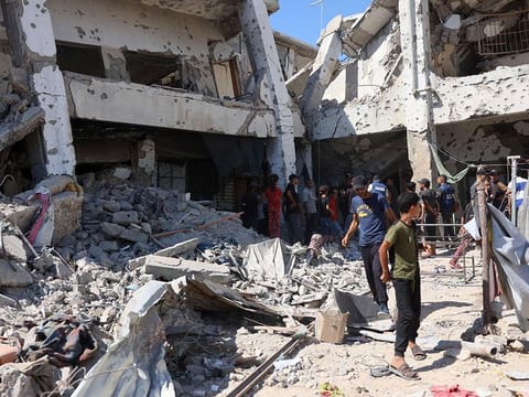 Palestinians check the damage in the Al Zahra school used as a refuge by displaced Palestinians following an Israeli strike, in the Shujaiya neighbourhood of Gaza