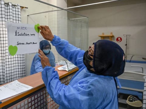 A health worker installs a poster indicating an isolation ward prepared for mpox patients at the Police and Services hospital in Peshawar on August 20, 2024.
