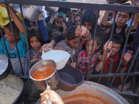 Palestinians receive food as part of a volunteer initiative in a makeshift displacement camp in Mawasi Khan Yunis in the besieged Gaza Strip on September 3, 2024.