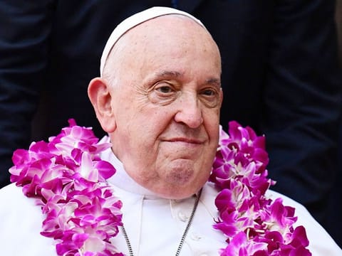 Pope Francis wears a flower garland as he arrives for an interreligious meeting with young people at the Catholic Junior College in Singapore on September 13, 2024.