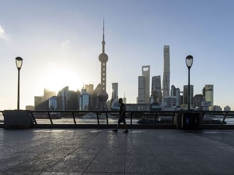 A pedestrian along the Bund across from commercial buildings in Pudong's Lujiazui Financial District in Shanghai, China. China’s central bank has announced a sweep of support for the economy, as pressure mounts on authorities to unleash stimulus and hit this year’s growth target of around 5%.
