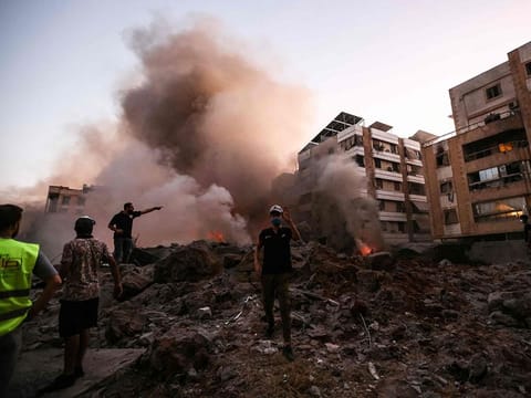 People and rescuers stand amid the rubble of a building destroyed in an Israeli air strike in the Haret Hreik neighbourhood of Beirut's southern suburbs on September 27, 2024.