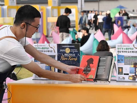 A staff member checks books by South Korean author Han Kang, who won the 2024 Nobel Prize in Literature, displayed during an outdoor library event at Gwanghwamun square in central Seoul on October 11, 2024. From the president to K-pop megastars BTS, South Korea erupted into celebration on October 10, after "The Vegetarian" author Han Kang won the country's first Nobel Prize for literature