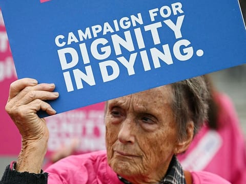 A campaigner from "Dignity in Dying" hold a placard during a demonstration outside The Palace of Westminster, home to the Houses of Parliament in central London, on October 16, 2024, during a gathering in favour of the proposal to legalise euthanasia in the UK.