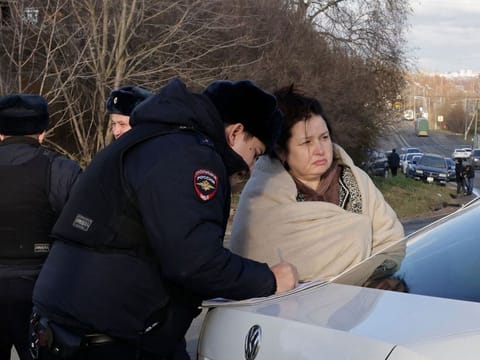 A Russian police officer questions a local resident at site of a drone attack in the village of Stanovoye, Moscow region, on November 10, 2024.