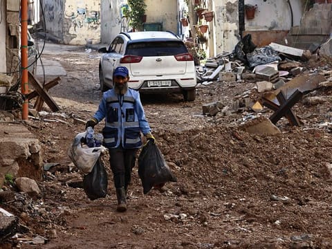 A UN worker clears the rubbish amid the destruction following an Israeli military raid in the occupied-West Bank city of Jenin on November 21, 2024.
