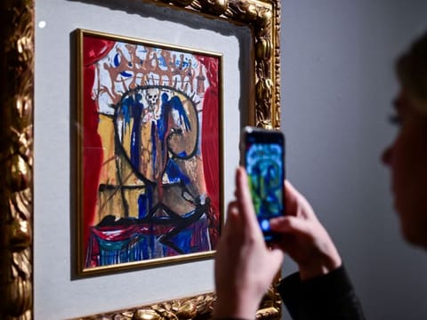 A visitor takes pictures of an illustration for Romeo and Juliet by Spanish artist Salvador Dali during a press preview of the exhibition titled "SalvArti, from Confiscations to Public Collections" at Palazzo Reale in Milan, Italy, on December 2, 2024. The exhibition, running from December 3, 2024 to January 26, 2025, showcases a series of contemporary artworks coming from confiscations carried out by public authorities against organised crime. (Photo by Piero CRUCIATTI / AFP) / RESTRICTED TO EDITORIAL USE - MANDATORY MENTION OF THE ARTIST UPON PUBLICATION - TO ILLUSTRATE THE EVENT AS SPECIFIED IN THE CAPTION