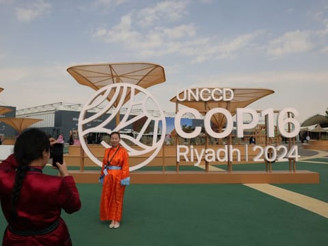Delegates take pictures outside the conference centre where the United Nations Convention to Combat Desertification, UNCCD COP16, was opened in the Saudi capital Riyadh on December 2, 2024.