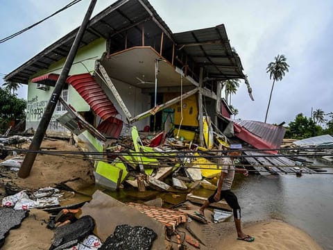 A man walks past a home damaged by flood waters in Tumpat, Malaysia's Kelantan state, on December 4, 2024