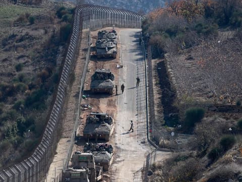 Israeli tanks and armoured vehicles line up the area outside the Druze village of Majdal Shams on the fence with the buffer zone that separates the Israeli-annexed Golan Heights from the rest of Syria on December 9, 2024.