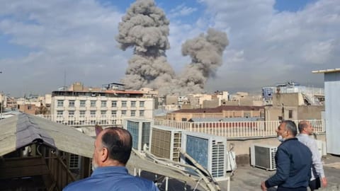 People watch as smoke rises on the skyline after an explosion in Tehran, Iran, Saturday, Feb. 28, 2026