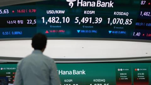 A dealer walks near the screens showing the Korea Composite Stock Price Index (KOSPI) and the foreign exchange rate between U.S. dollar and South Korean won at a dealing room of Hana Bank in Seoul, South Korea, Wednesday, March 4, 2026.