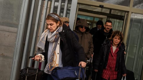 People, mostly Iranians who crossed from Iran at the Kapikoy border crossing, pull luggage in Turkey’s eastern Van province, Friday, March 6, 2026.