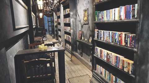 A narrow passage lined with bookshelves and cafe tables at the entrance of Moore
Market & Retro Coffee