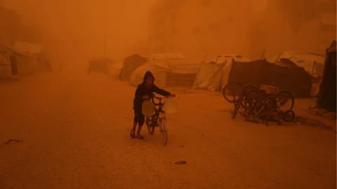 A boy pushes a bicycle carrying jerrycans of water through a sandstorm in Khan Younis, southern Gaza Strip, Saturday, March 14, 2026. 