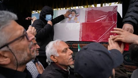 Iranians reach toward the coffins as they follow the funeral procession of Iran’s intelligence minister Esmail Khatib and, according to Iranian officials, his wife and daughter, in Tehran, Iran