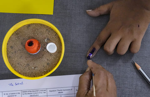 A voter gets her finger marked with indelible ink while casting vote