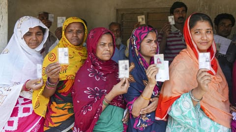 Women wait in a queue before voting in the first phase of the West Bengal Assembly elections, at a polling station in Panskura, Purba Medinipur
