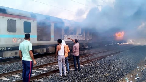People gather after a fire broke out in an AC coach of the Thiruvananthapuram-Hazrat Nizamuddin Rajdhani Express in Madhya Pradesh's Ratlam district
