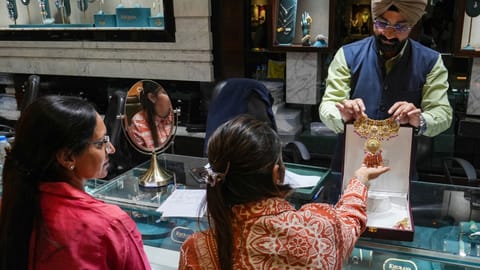 A salesperson shows a necklace to customers at a jewellery shop, in Amrisar, Punjab, Wednesday, May 13, 2026. Jewellers and industry leaders on Wednesday said the hike in import duty on gold and silver could impact jewellery volumes in the short term, though demand is expected to remain resilient due to the yellow metal's enduring cultural and investment appeal in India (PTI)
