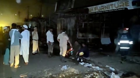 Police personnel and people gather after a fire broke out at a furniture market, in Shastri Park, New Delhi
