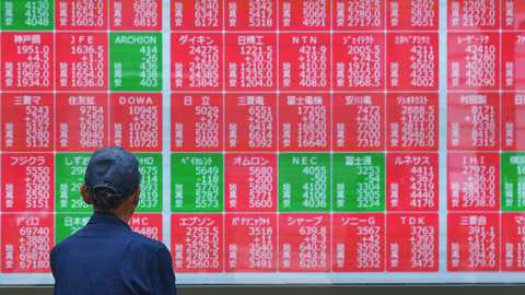 A person looks at an electronic stock board showing Japan’s Nikkei index at a securities