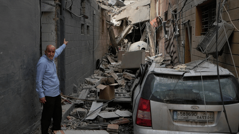  A man points into a destroyed building that was hit in an Israeli airstrike in Burj al-Shemali village