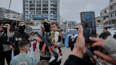 Palestinians take photos with Islamic Jihad militants as they gather for Eid al-Adha prayers in Gaza City Wednesday, May 27, 2026.