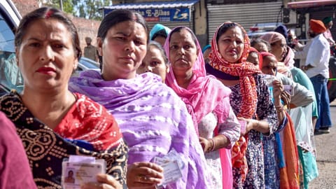 People show their identity cards as they wait in a queue at a polling station to cast their votes during the Municipal Corporation elections, in Amritsar, Punjab
