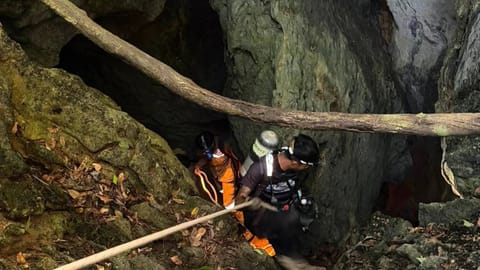 Rescuers try to reach people who have been trapped in a cave