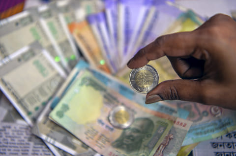 Siliguri: A woman displays a Rs 20 coin along with Indian currency notes amid market fluctuations following India-US trade developments, in Siliguri, Tuesday,