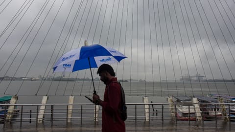 A man covers himself during rainfall as monsoon arrives, at Marine Drive, in Kochi, Kerala, Friday, June 5, 2026