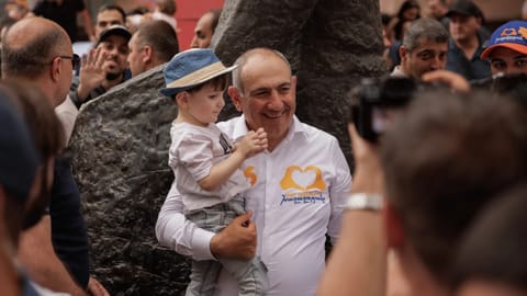 Armenian Prime Minister Nikol Pashinyan holds a child as he walks on Northern Avenue in Yerevan, Armenia