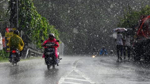 Commuters move along a street during rainfall, in Thiruvananthapuram, Kerala