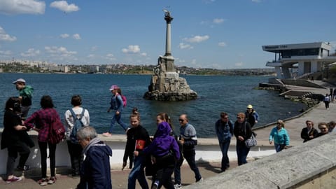 Tourists walk along an embankment in Sevastopol, Crimea