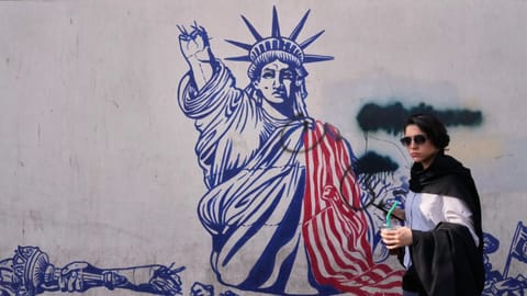 Woman walks past an anti-American mural on the wall of the former U.S. Embassy